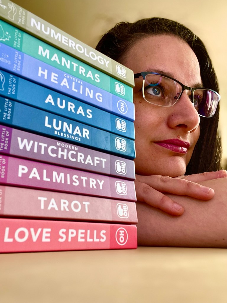 Katalin's face looking into the distance. In the foreground, a stack of the books she has written so far.