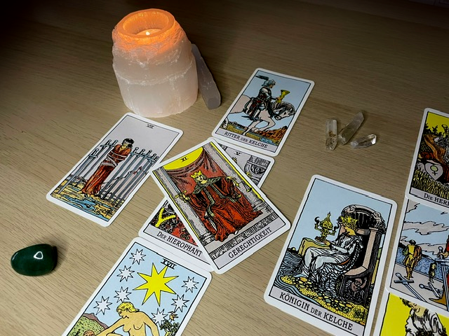 A tarot spread with a lit candle in a selenite candle holder, and some crystals strewn over the table.